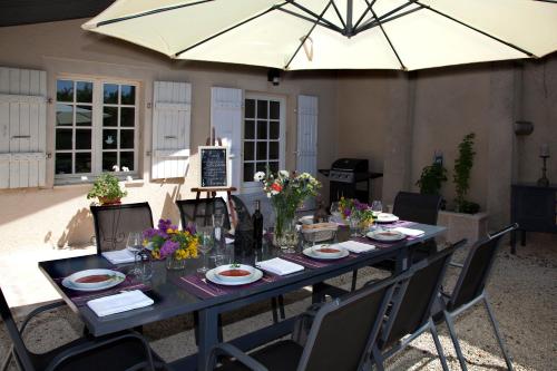 une grande table avec des chaises et un parasol dans l'établissement Maison d'hôtes de Charme Les Bruhasses, à Condom