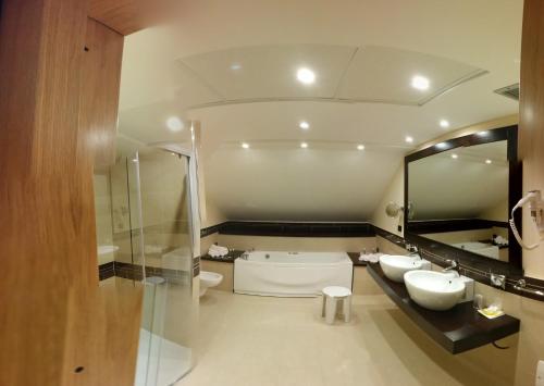 bagno con 2 lavandini, vasca e specchio di Uliveto Principessa Resort a Cittanova