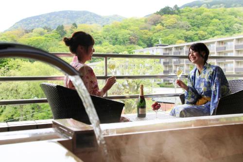 
two people sitting on a balcony looking at their cell phones at Merveille Hakone Gora in Hakone

