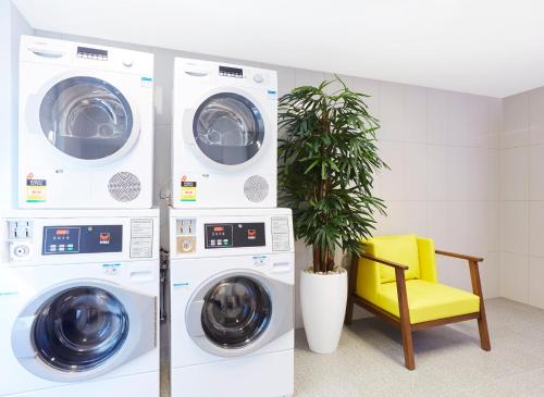 two washing machines and a yellow chair in a room at Holiday Inn Express Brisbane Central by IHG in Brisbane