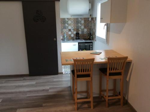 a kitchen with a wooden table and two chairs at Le studio de la plage in Perros-Guirec