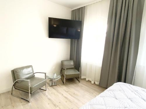 a bedroom with two chairs and a tv on the wall at GrandLux Villa & Spa in Teplice