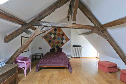 Cette chambre mansardée comprend un lit et deux chaises. dans l'établissement Chambre Coton au Moulin de gâteau, à Saint-Pierre-les-Étieux