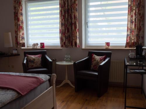 a bedroom with two chairs and a bed and windows at Wegeners Landhaus UG in Uelzen