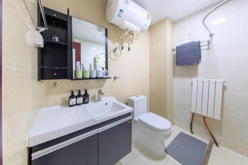 a bathroom with a sink and a toilet and a mirror at Tianjin Xiqing·University Town· in Tianjin