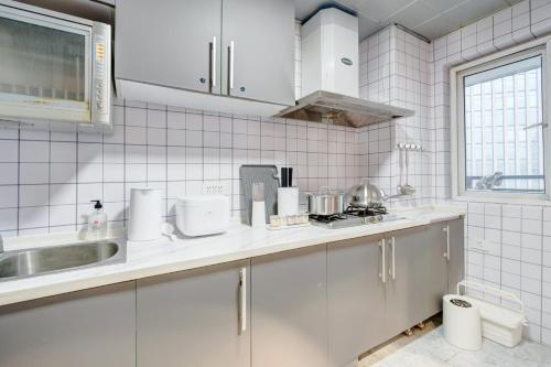a white tiled kitchen with white cabinets and a sink at Wuhan City Wuchang District shahu park in Pingdingshan