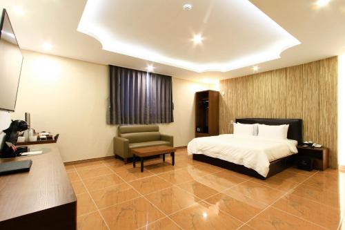 a hotel room with a bed and a chair at The King Hotel in Busan