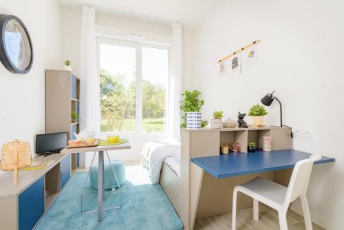 un bureau à domicile avec un bureau bleu et une table dans l'établissement Résidence SWEETLY Alexandrin, à Toulouse