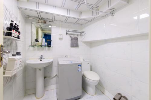 a white bathroom with a toilet and a sink at Tianjin Hedong·Wanda Plaza· in Tianjin