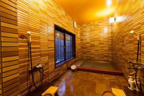 a bathroom with a bath tub and a window at Tsuruya Ryokan in Toyooka