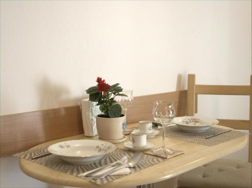 a wooden table with plates and glasses and a table cloth at Anna Apartment in Braşov