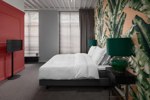 a bedroom with a white bed and a colorful wall at Boutique Hotel De Vier Patriciërs in Middelburg