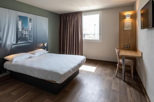 トロワにあるB&B HOTEL Troyes Magasins d'usineのベッド、デスク、窓が備わるホテルルームです。