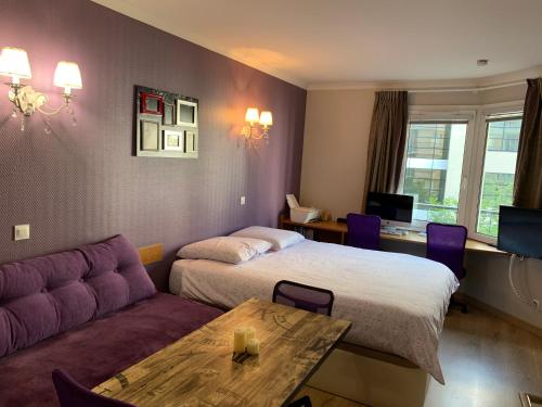 イシー・レ・ムリノーにあるALTAMIRA (Paris Expo - Porte de Versailles)のベッド2台とソファが備わるホテルルームです。
