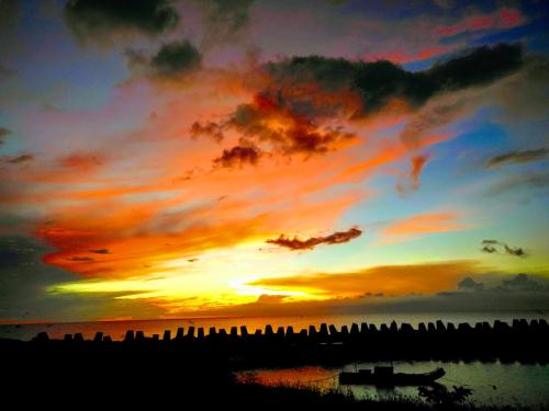 a sunset with a group of buildings in the water at 墾丁后灣仙杜瑞拉海景旅宿 in Checheng