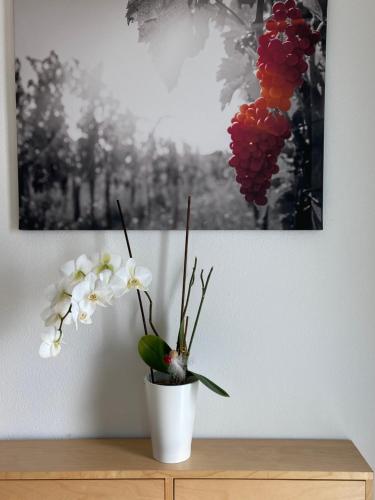 a white vase with flowers on a wooden table at Ferienwohnung Weinbergblick in Mehring