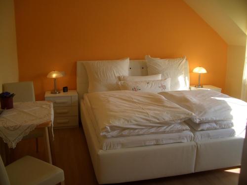 un letto bianco con lenzuola e cuscini bianchi in una camera da letto di Ferienwohnungen Schulze Oppach Oberlausitz - 5 Sterne a Oppach