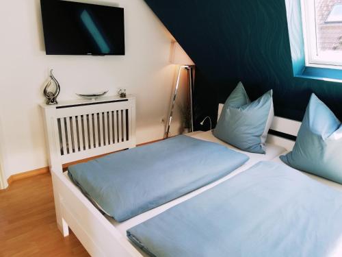 a bedroom with two beds with blue pillows and a tv at Bernstein in Zingst