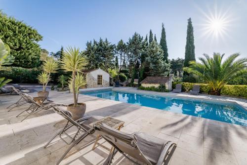 - une piscine avec 2 chaises longues et des arbres dans l'établissement La Bastide de Font Clarette, à Six-Fours-les-Plages