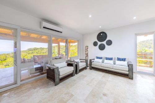 a living room with white furniture and large windows at VILLA ROA in Roatan