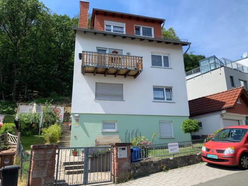 una casa con balcón y un coche rojo aparcado delante en Ferienwohnung Wolff, Kelkheim, en Kelkheim