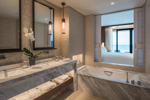 a bathroom with two sinks and a tub and a bedroom at Amara - Sea Your Only View™ in Limassol