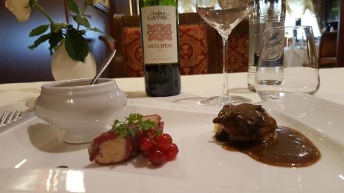 a white plate with food on a table with a bottle of wine at Hotel Re'ser Stuff in Roeser