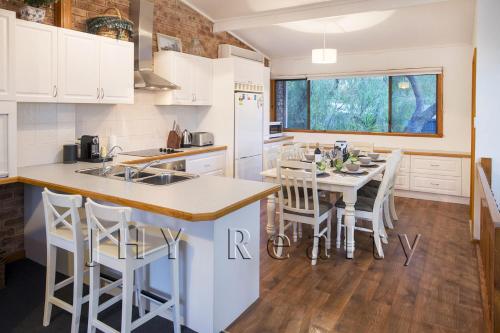 a kitchen with white cabinets and a table with chairs at Coastal Cottage in Quindalup