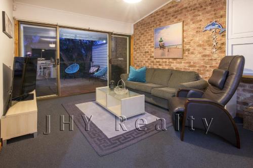 a living room with a couch and a tv at Coastal Cottage in Quindalup