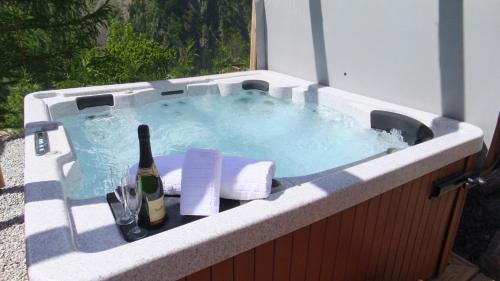 a hot tub with a bottle of wine and a glass at Chalet Morville in Vénosc