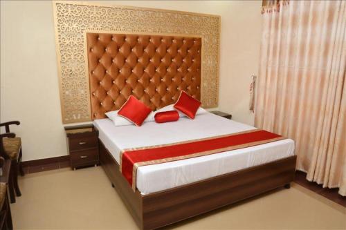 - une chambre avec un grand lit et des oreillers rouges dans l'établissement Executive Palace Hotel, à Lahore