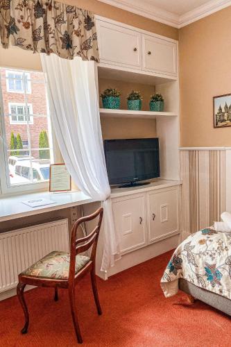 a bedroom with a tv and a chair and a window at American House Hennela in Warsaw
