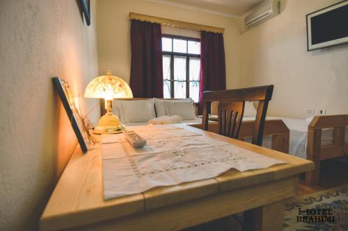 een kamer met een tafel met een lamp en een bank bij Hotel Brahimi in Gjirokastër