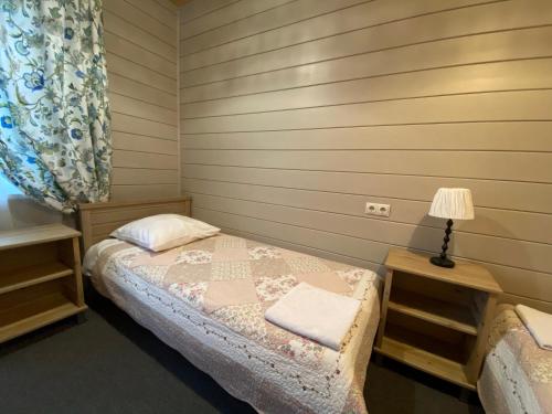 a small bedroom with a bed and a lamp at Usadba Demidova in Listvyanka