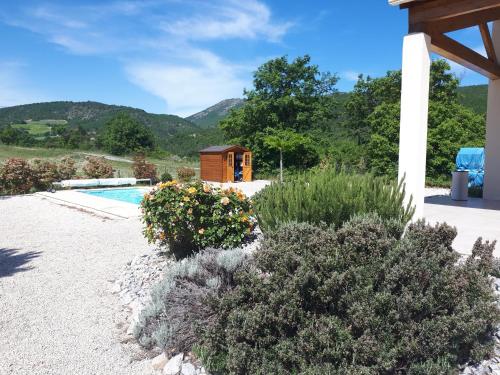 a garden with a pool and mountains in the background at LES HAUTS DE JALLIA in Sainte-Jalle