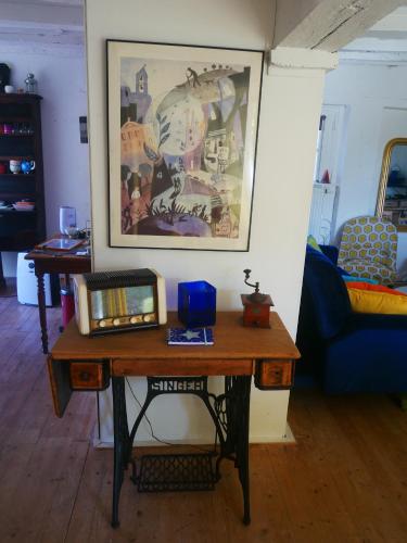 a table in a living room with a picture on the wall at Au Coeur de la Cour in Saint-Georges-sur-Cher