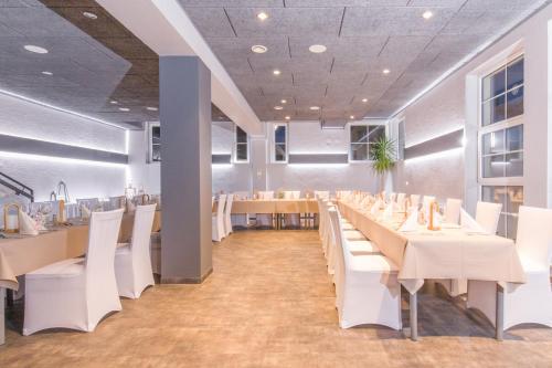 un comedor con mesas blancas y sillas blancas en Hotel & Restaurant 5 Linden en Wickerode