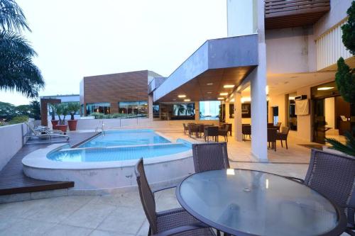 a patio with a table and chairs and a swimming pool at Indaiá Park Hotel in Campo Grande