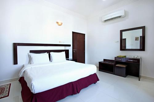 a white bedroom with a large bed and a mirror at Star Emirates Furnished Apartment in Salalah