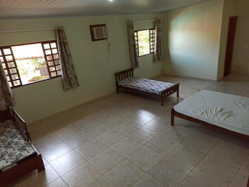 Schlafzimmer mit einem Bett, einer Bank und Fenstern in der Unterkunft Sítio Recanto da Paz - Chácara para temporada com piscina aquecida in Hidrolândia