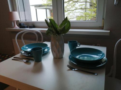a table with two plates and a vase with a plant at Apartamenty Przy Rynku in Żnin