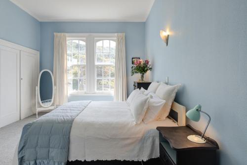 a blue bedroom with a large bed and a window at Thorndon Heritage Listed Villa in Wellington