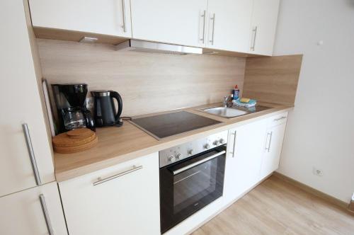 een keuken met witte kasten, een wastafel en een fornuis bij Appartementhaus Nige Ooge Ferienwohnung Nr. 3 in Cuxhaven