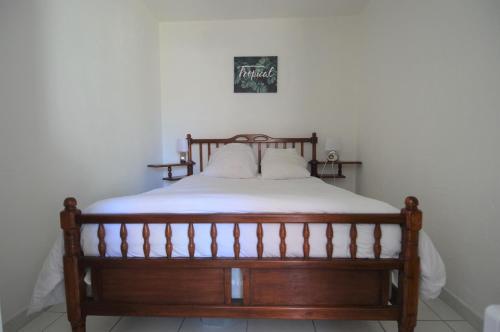 a bedroom with a wooden bed with white sheets at Maisonnette avec terrasse à 50m de la plage in Luc-sur-Mer