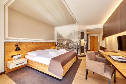 una camera d'albergo con letto, scrivania e sedie di Hotel am Badersee a Grainau