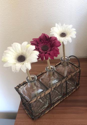 three flowers in vases in a basket on a table at Ferienwohnung Winkler in Rothenburg ob der Tauber