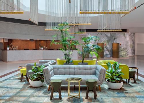 una hall con divano, tavoli e piante in vaso di Vert Hotel Eilat by AFI Hotels a Eilat