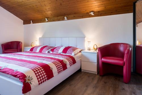 ein Schlafzimmer mit einem roten Bett und zwei roten Stühlen in der Unterkunft Chalet Ravenstein in Fiesch