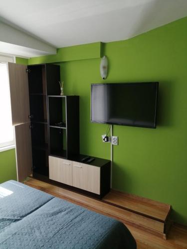 - une chambre dotée d'une télévision à écran plat sur un mur vert dans l'établissement Top Center Apartment and Rooms Varna, à Varna