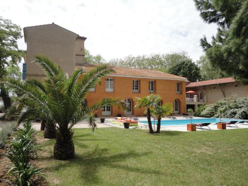 a house with a palm tree and a swimming pool at La Gourgasse Vieille in Béziers